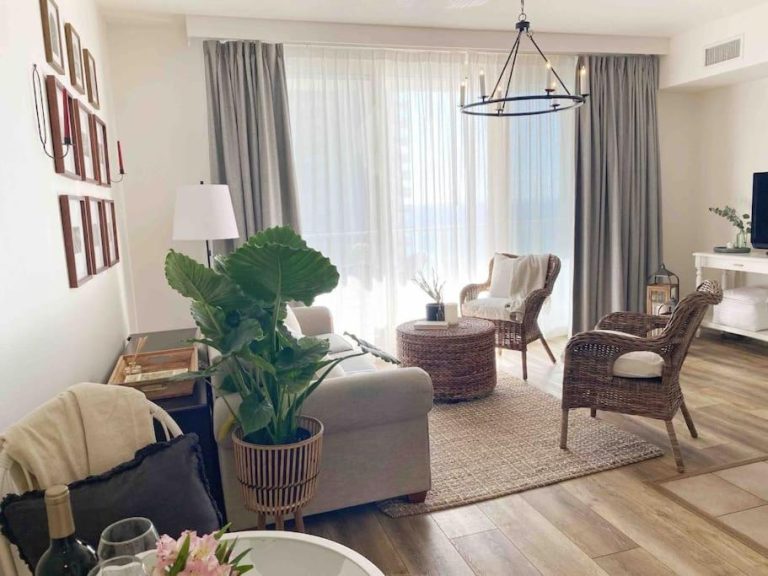 Salón luminoso con sillas de ratán y planta tropical en Shores of Panama Unit 1209, Panama City Beach