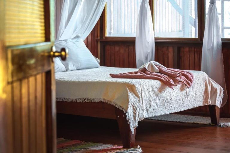Habitación rústica con cama de dosel y paredes de madera en Ocean Forest Ecolodge