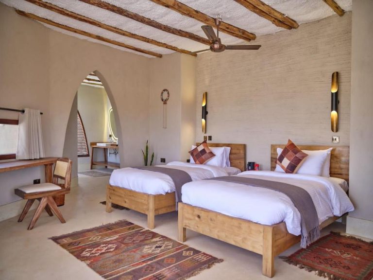 Habitación doble con camas de madera y decoración rústica africana en Surana Buffalo Springs