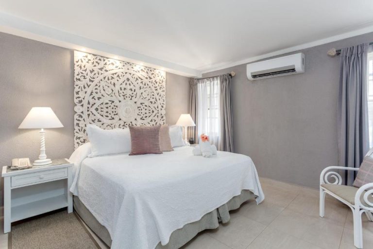 Habitación doble elegante con cama king y cabecero tallado en blanco del Sugar Bay Barbados All Inclusive