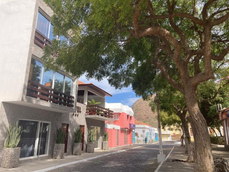 Calle empedrada colonial frente al Hotel Viajante con edificios coloridos y montañas al fondo