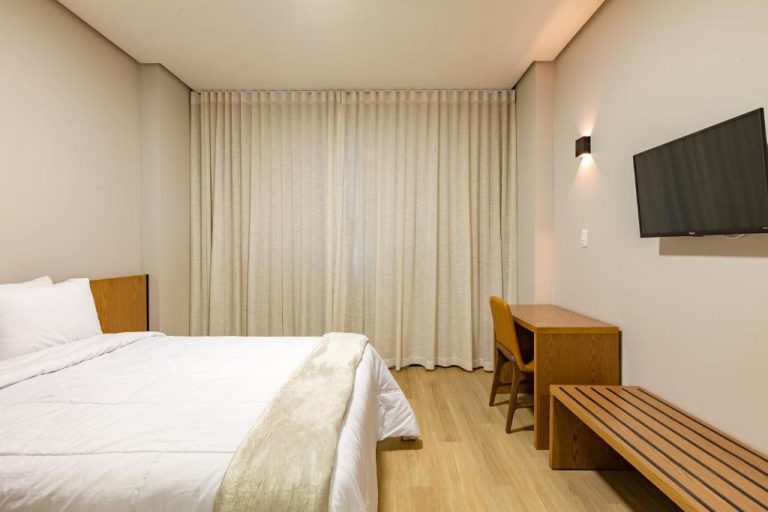 Habitación doble con cama, escritorio de madera y TV del Tri Hotel Antônio Prado