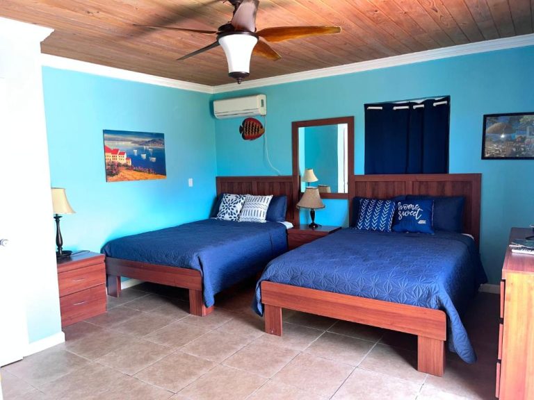Habitación doble con camas azules y techo de madera en Bay Inn Estates