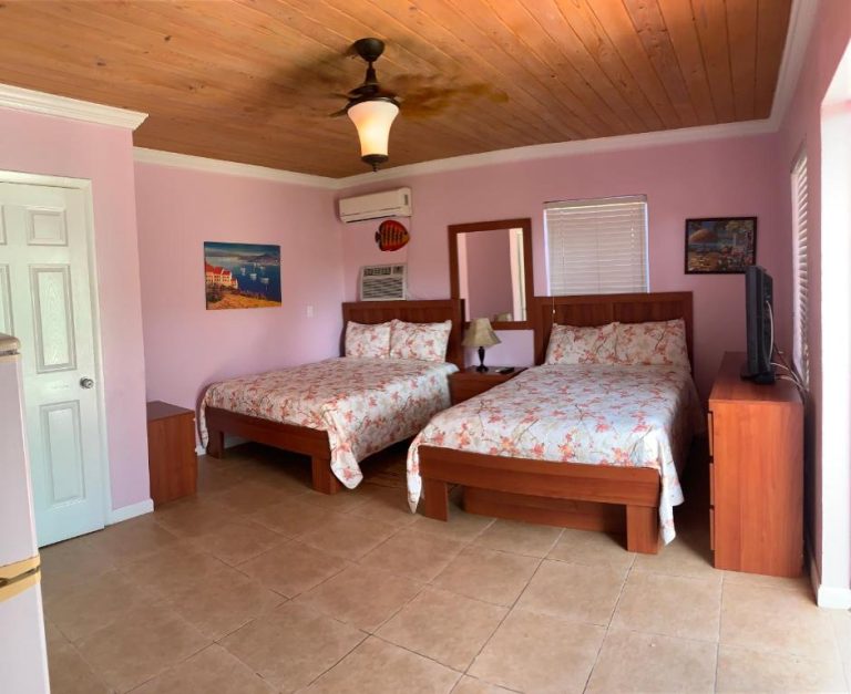 Habitación doble con dos camas y techo de madera en Bay Inn Estates, decoración tropical
