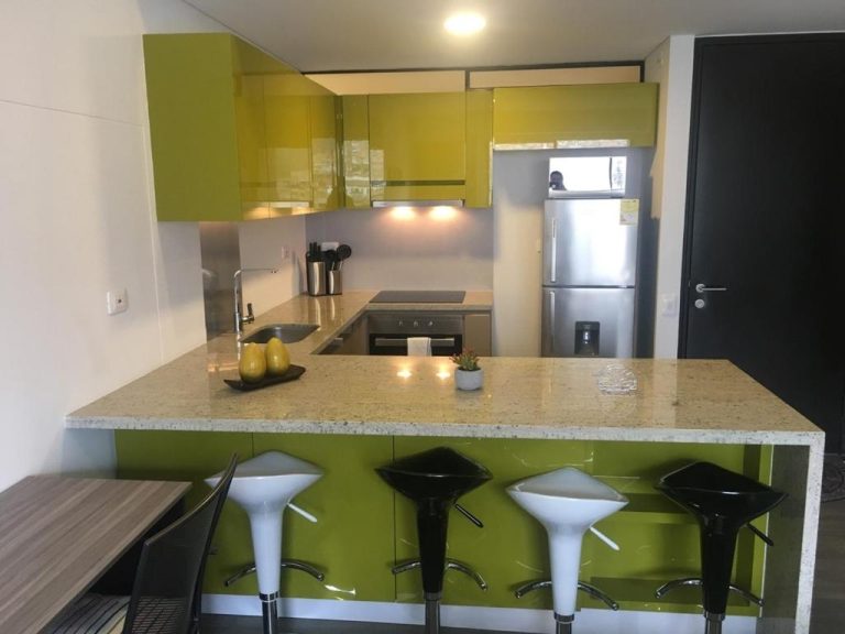 Cocina equipada con barra de desayuno y taburetes modernos en el apartamento Enjoy In Bogotá