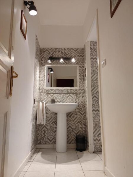 Baño con lavabo de pedestal y pared de azulejos decorativos en Hotel Biscari
