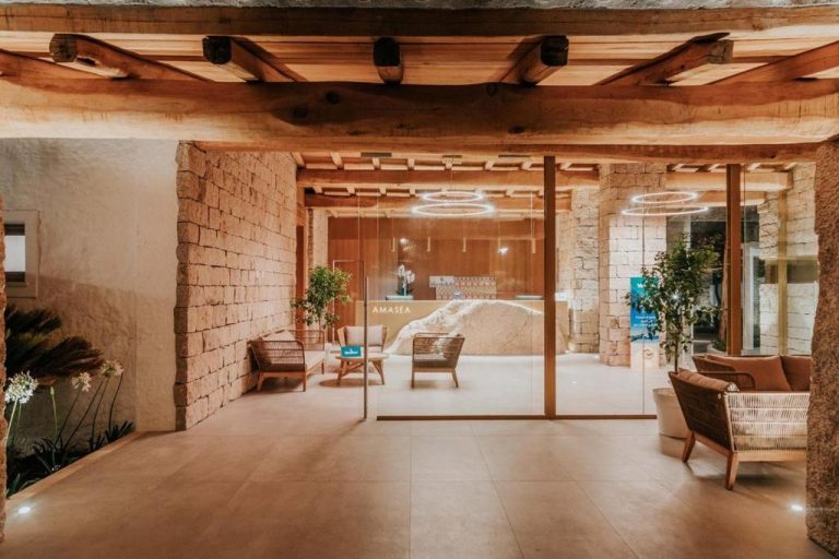 Recepción del AMASEA Resort con paredes de piedra natural, vigas de madera y elegante zona de espera
