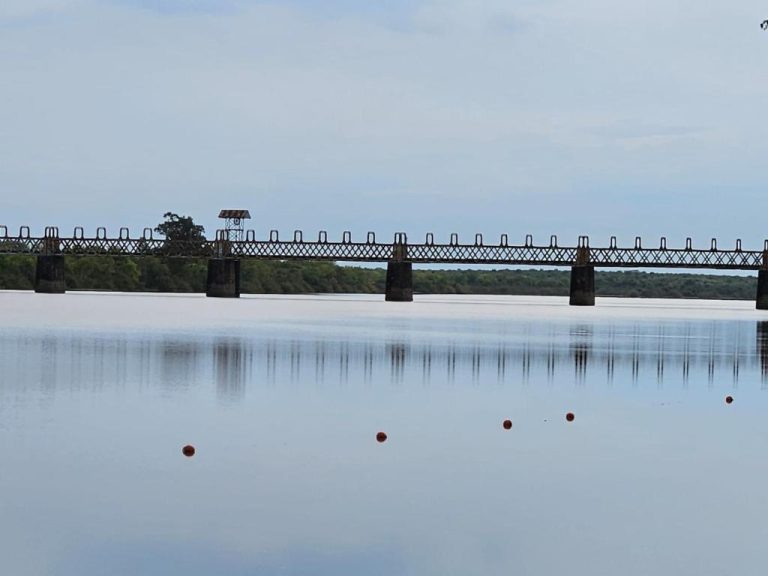 Puente histórico de hierro sobre el río Negro reflejado en el agua, vista desde Hotel Terrazas del Río Negro