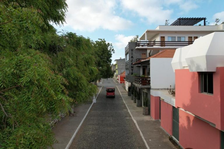 Calle de acceso al Hotel Viajante con edificios coloridos y vegetación en Cabo Verde