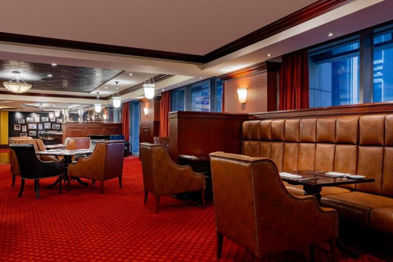 Elegante salón restaurante con cabinas de cuero marrón y alfombra roja en Marriott Marquis City Center Doha