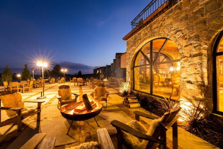 Terraza exterior con fogata y sillas rústicas del Cerro Azul Hotel Fazenda iluminada de noche