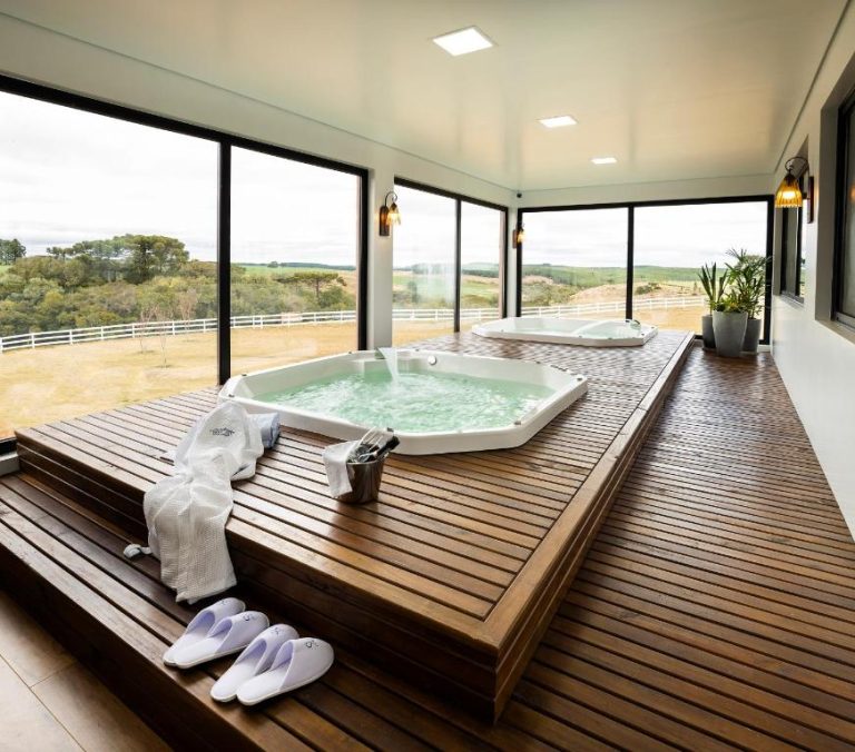 Jacuzzi interior con deck de madera y vistas al campo en Cerro Azul Hotel Fazenda