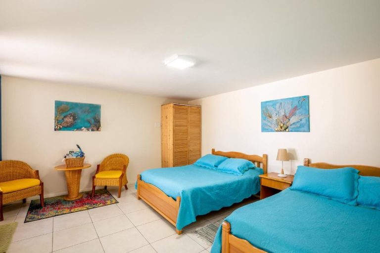 Habitación doble con dos camas azules y decoración tropical en Serene by the Sea