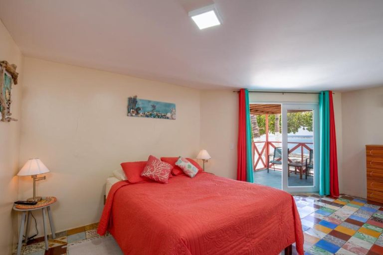 Habitación con cama doble roja y terraza con vista al mar en Serene by the Sea