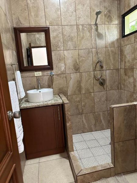 Baño moderno con ducha abierta y lavabo sobre encimera de granito en Hotel Real Paraíso