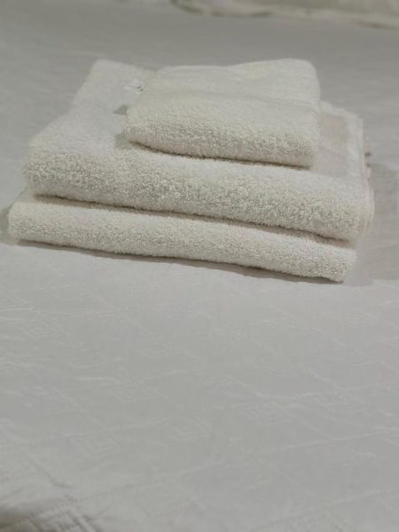 Toallas blancas esponjosas dobladas sobre la cama del Hotel Real Paraíso, listas para los huéspedes