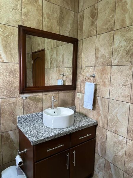 Baño moderno con lavabo redondo sobre encimera de granito y espejo en Hotel Real Paraíso