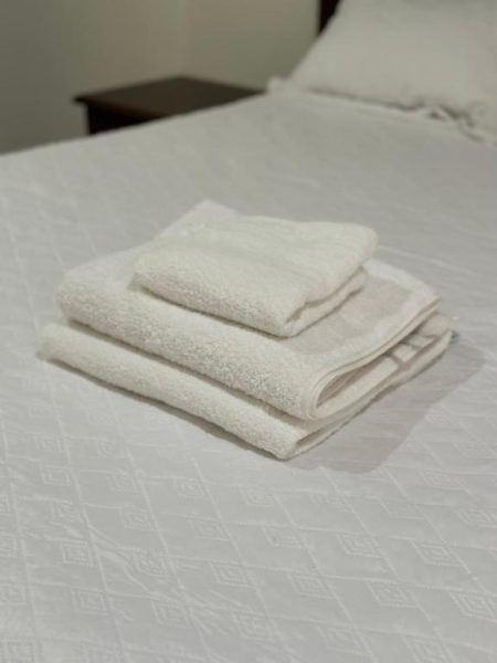 Toallas blancas limpias y dobladas sobre la cama de una habitación del Hotel Real Paraíso