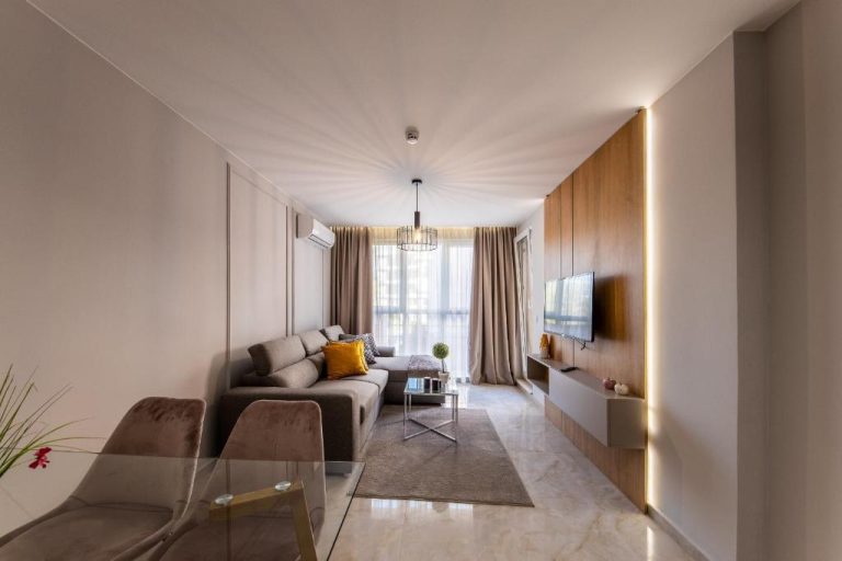 Salón moderno con sofá, televisión y panel de madera iluminado en Emilia Romana Park