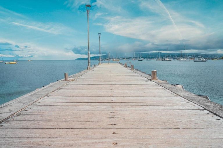 Embarcadero de madera con vistas al mar y veleros del Hotel Bambou en día despejado