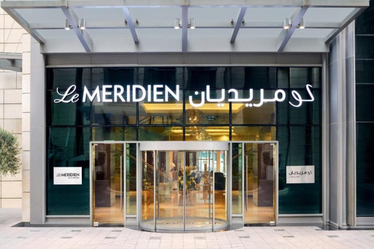 Entrada principal con puerta giratoria del Le Meridien City Center Doha con rótulo en árabe