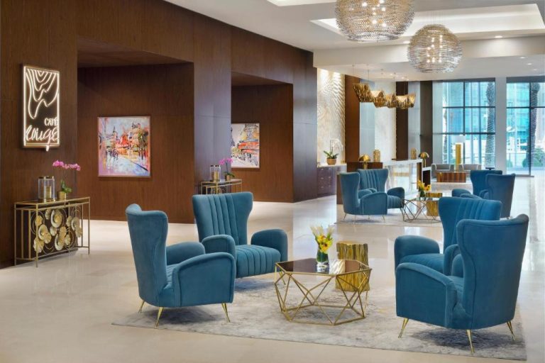 Elegante lobby lounge del Le Meridien City Center Doha con sillones azules y lámparas de araña