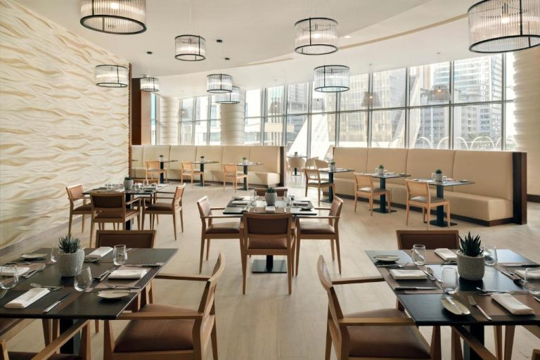 Restaurante moderno con vistas a la ciudad en Le Meridien City Center Doha, mesas elegantes y luz natural