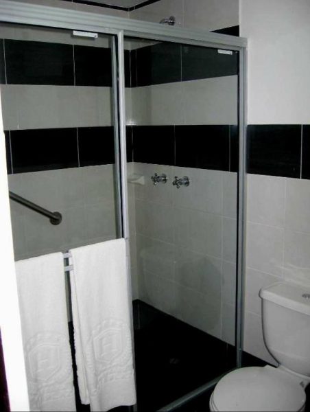 Baño con ducha de cristal en blanco y negro del AW Hotel Sport con toallas blancas