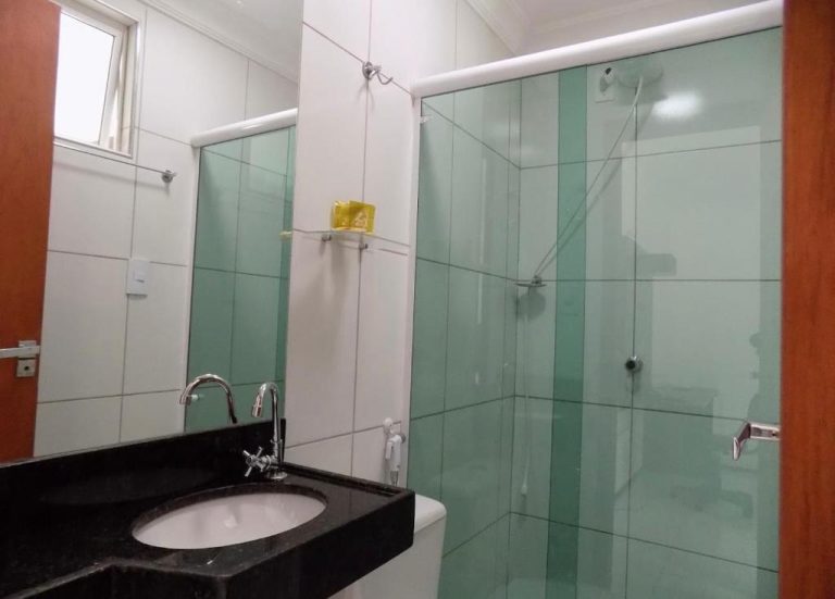 Baño moderno con ducha de cristal y lavabo de mármol negro en Hotel Sol Brasil