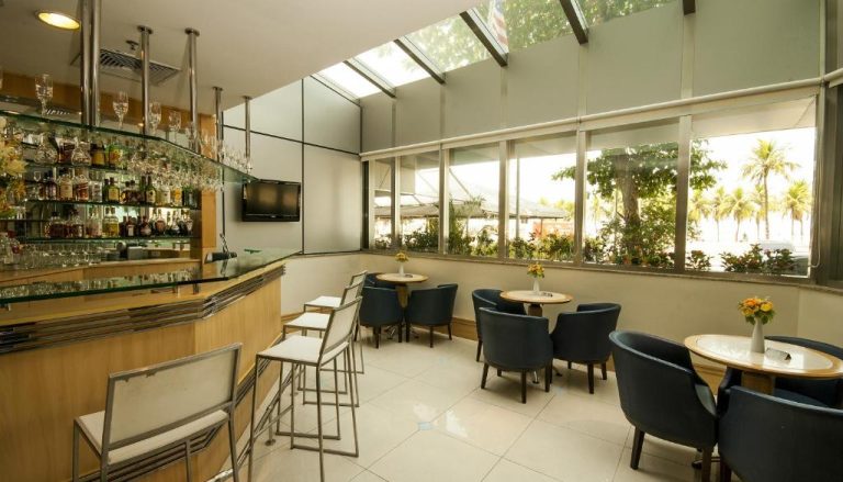 Bar y salón interior elegante con zona de cócteles y terraza acristalada del Hotel Astoria Palace