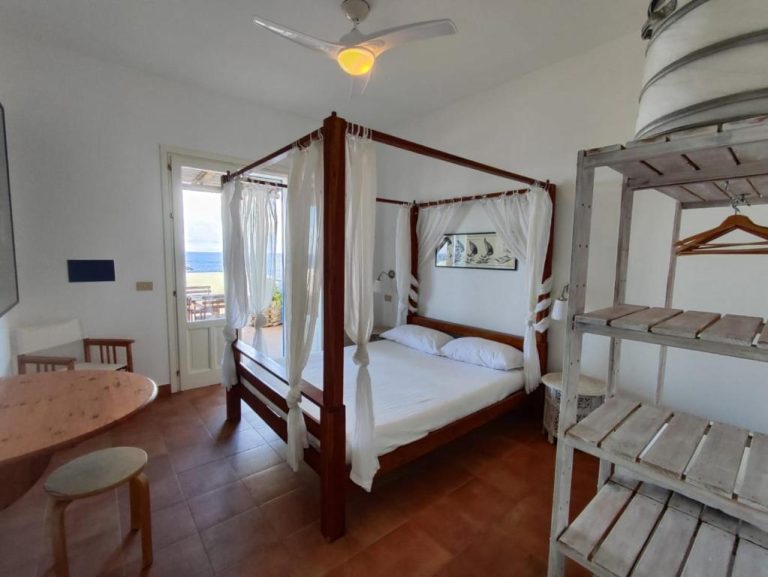 Habitación con cama de dosel de madera y vistas al mar en Marettimo Residence
