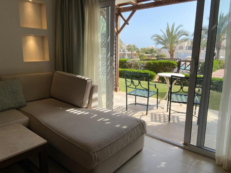 Salón con sofá y acceso a terraza con vistas al jardín y palmeras en Hotel Studio