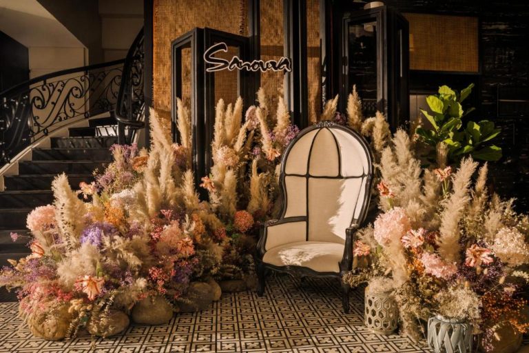 Entrada del Sanouva Da Nang Hotel decorada con flores secas y sillón clásico de estilo elegante