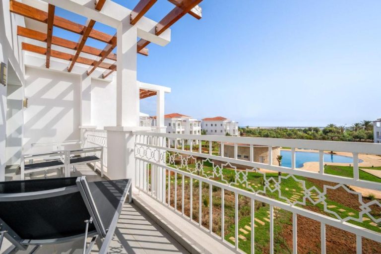 Terraza con sillas y pérgola de madera con vistas a la piscina exterior en Radisson Blu Residences Saidia