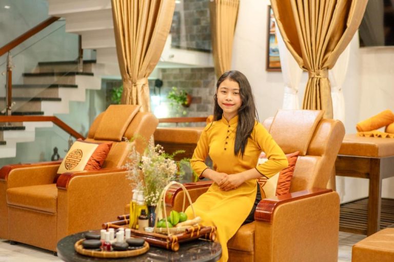Recepcionista con vestido ao dai amarillo en la zona de spa del Hannah House Hoi An