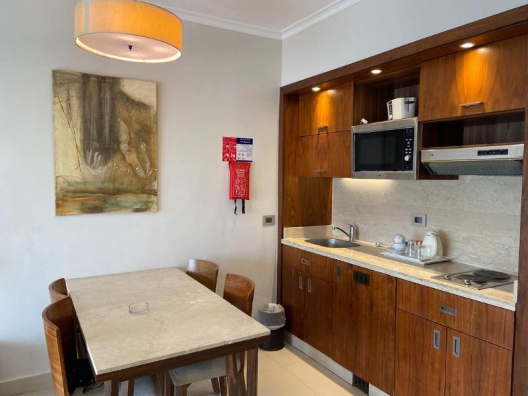 Cocina equipada con microondas, fregadero y mesa de comedor de madera en Hotel Studio