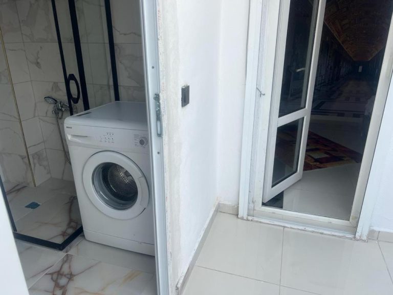 Lavadora y zona de ducha en el baño interior del Tourist Pansiyon 2 con suelo de mármol