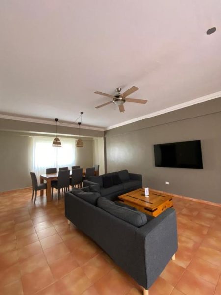 Salón comedor abierto con sofá, TV y mesa de comedor en apartamento del hotel Bavaro Green