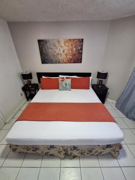 Habitación con cama doble y decoración naranja en Beach One Bedroom 2 con lámparas de noche