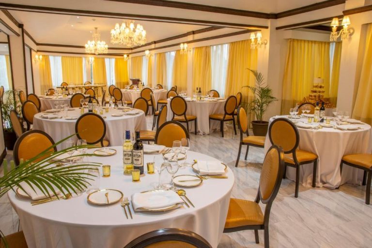 Salón de banquetes elegante con mesas redondas y decoración dorada en el Sago Palm Hotel