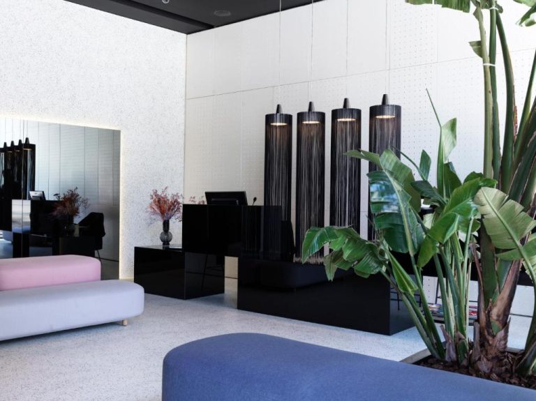 Recepción moderna del MAP Boutique Hotel con lámparas negras colgantes, plantas tropicales y sofás de diseño
