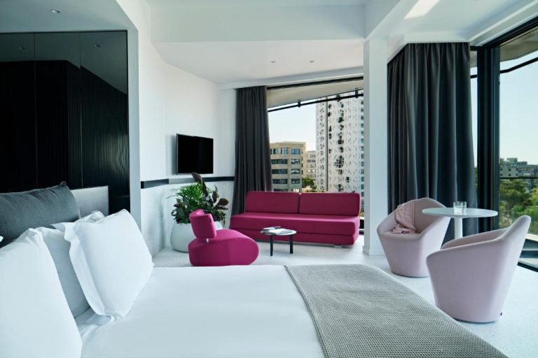 Suite de diseño moderno con sofá fucsia y vistas a la ciudad en MAP Boutique Hotel