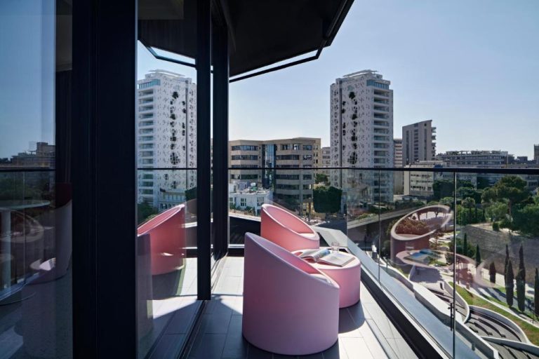 Terraza con sillones rosas y vistas panorámicas a la ciudad en MAP Boutique Hotel