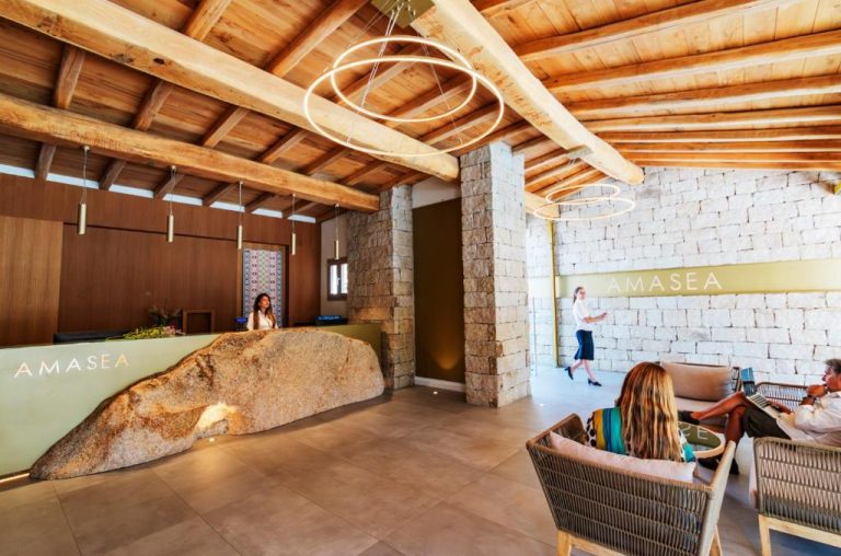 Recepción con mostrador de piedra natural y techo de madera del AMASEA Resort