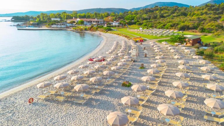 Playa privada del AMASEA Resort con sombrillas y tumbonas frente al mar turquesa de Cerdeña