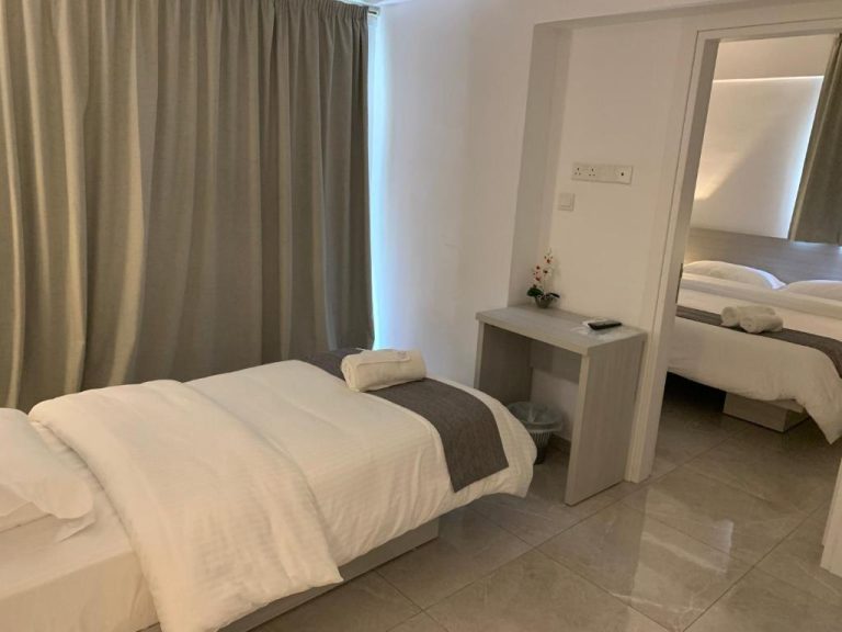 Habitación doble con dos camas individuales y espejo en La Veranda Hotel, decoración moderna en tonos blancos