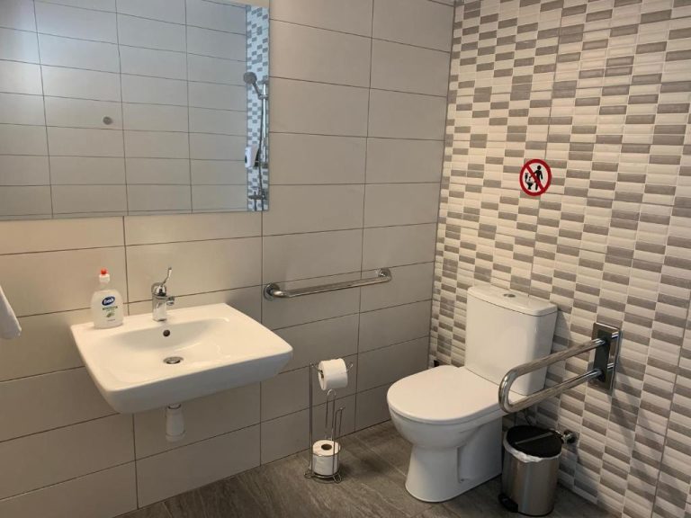 Baño adaptado para personas con movilidad reducida en La Veranda Hotel con barras de apoyo y lavabo accesible