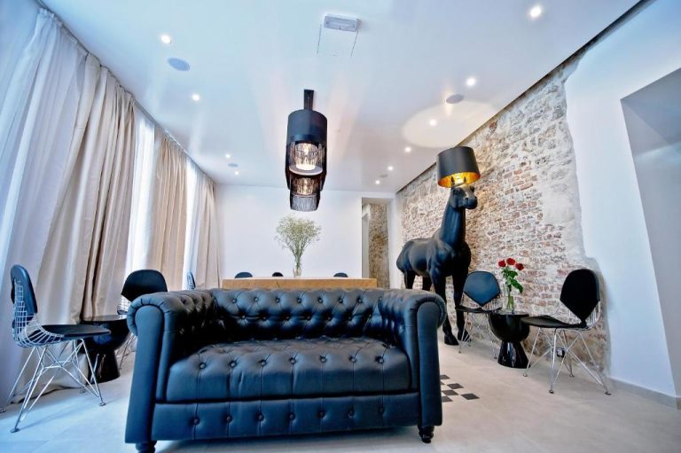 Salón de diseño moderno con sofá Chester negro y escultura de caballo en Jupiter Heritage Hotel