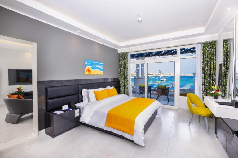 Habitación de lujo con cama doble y vistas al mar turquesa en Naama Bay Suites & SPA