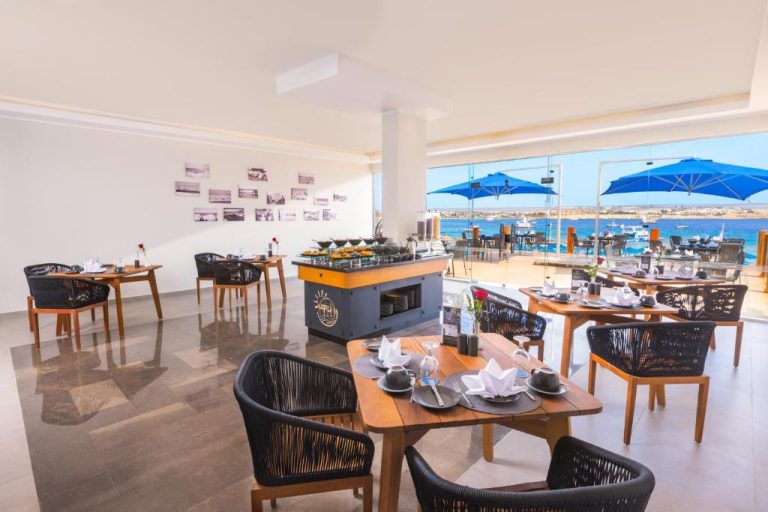 Restaurante interior con vistas al mar del Naama Bay Suites & SPA, mesas elegantes y terraza exterior